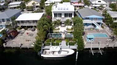Florida, ABD 'deki hava aracı videosu, ticari alan, lüks evler, binalar ve malikaneler, mavi gökyüzü, okyanus ve tekneleri olan güzel bir sahilde bol miktarda tropikal bitki örtüsü..