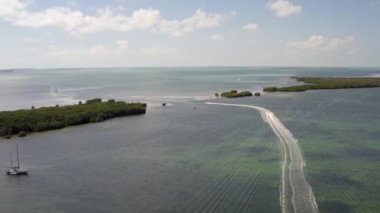 Florida, ABD 'deki hava aracı videosu, ticari alan, lüks evler, binalar ve malikaneler, mavi gökyüzü, okyanus ve tekneleri olan güzel bir sahilde bol miktarda tropikal bitki örtüsü..