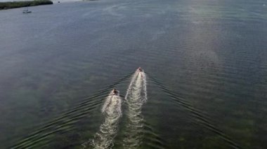 Florida, ABD 'deki hava aracı videosu, ticari alan, lüks evler, binalar ve malikaneler, mavi gökyüzü, okyanus ve tekneleri olan güzel bir sahilde bol miktarda tropikal bitki örtüsü..