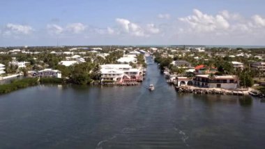 Florida, ABD 'deki hava aracı videosu, ticari alan, lüks evler, binalar ve malikaneler, mavi gökyüzü, okyanus ve tekneleri olan güzel bir sahilde bol miktarda tropikal bitki örtüsü..
