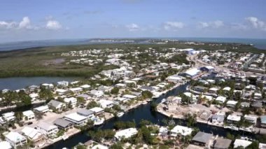 Florida, ABD 'deki hava aracı videosu, ticari alan, lüks evler, binalar ve malikaneler, mavi gökyüzü, okyanus ve tekneleri olan güzel bir sahilde bol miktarda tropikal bitki örtüsü..