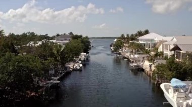 Florida, ABD 'deki hava aracı videosu, ticari alan, lüks evler, binalar ve malikaneler, mavi gökyüzü, okyanus ve tekneleri olan güzel bir sahilde bol miktarda tropikal bitki örtüsü..