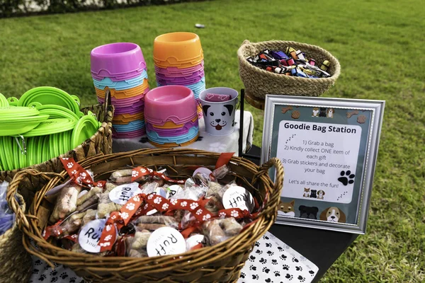 Outside Pet Dog Event Meeting Expo on Public Park with Green Short Grass in USA. Table with Dog plates, Handmade Baskets showcasing Dog Treats, Leashs and Toys.