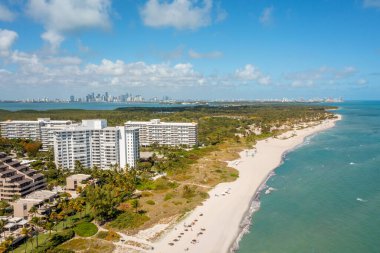 Florida, ABD 'deki hava aracı fotoshoot görüntüleri, ticari alan, lüks evler, binalar ve malikaneler, çevrede bol miktarda tropikal bitki örtüsü, mavi gökyüzü ve botlu su kanalı.