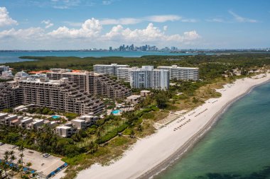 Florida, ABD 'deki hava aracı fotoshoot görüntüleri, ticari alan, lüks evler, binalar ve malikaneler, çevrede bol miktarda tropikal bitki örtüsü, mavi gökyüzü ve botlu su kanalı.