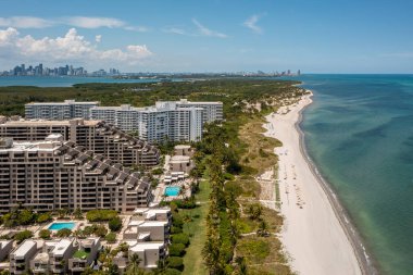 Florida, ABD 'deki hava aracı fotoshoot görüntüleri, ticari alan, lüks evler, binalar ve malikaneler, çevrede bol miktarda tropikal bitki örtüsü, mavi gökyüzü ve botlu su kanalı.