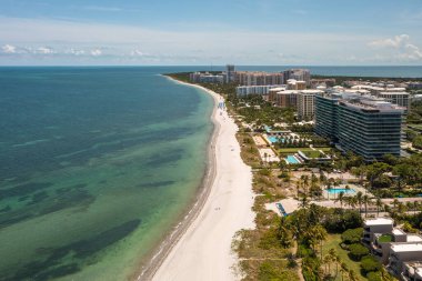 Florida, ABD 'deki hava aracı fotoshoot görüntüleri, ticari alan, lüks evler, binalar ve malikaneler, çevrede bol miktarda tropikal bitki örtüsü, mavi gökyüzü ve botlu su kanalı.