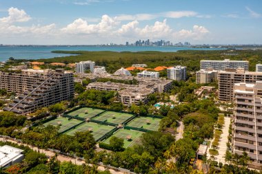 Florida, ABD 'deki hava aracı fotoshoot görüntüleri, ticari alan, lüks evler, binalar ve malikaneler, çevrede bol miktarda tropikal bitki örtüsü, mavi gökyüzü ve botlu su kanalı.