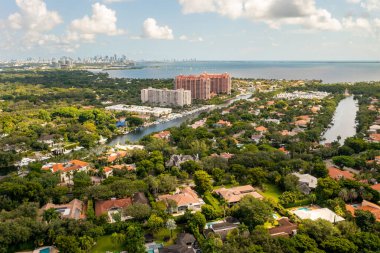 Florida, ABD 'deki hava aracı fotoshoot görüntüleri, ticari alan, lüks evler, binalar ve malikaneler, çevrede bol miktarda tropikal bitki örtüsü, mavi gökyüzü ve botlu su kanalı.