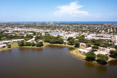 Florida, ABD 'deki hava aracı fotoshoot, ticari alan, lüks evler, binalar ve malikaneler, turkuaz suyu, mavi gökyüzü ve su kanalı etrafında bol miktarda tropikal bitki örtüsü.