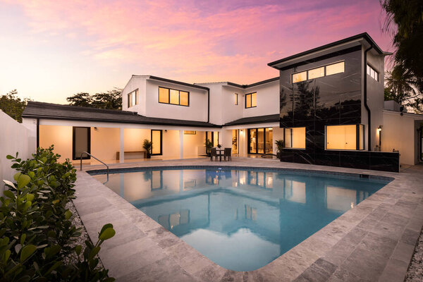 Современное здание с бассейном, деревьями, стульями. Городской пейзаж с голубым небом, отражающий бассейн и океан, архитектуру города и живописную окружающую среду, расположенную во Флориде, США.