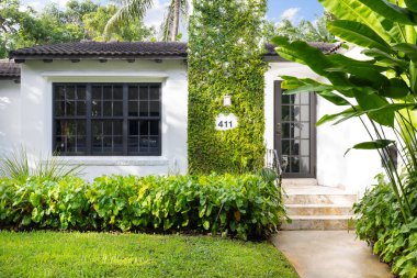 Modern mimari tasarım, ahşap mobilya, güzel yeşil bitki örtüsü, Mavi gökyüzü bulutları ve doğa sergilenmektedir..