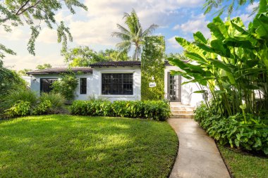 Modern mimari tasarım, ahşap mobilya, güzel yeşil bitki örtüsü, Mavi gökyüzü bulutları ve doğa sergilenmektedir..