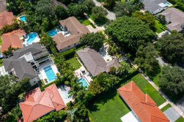 Florida, ABD 'deki hava aracı fotoshoot, ticari alan, lüks evler, binalar ve malikaneler, turkuaz suyu, mavi gökyüzü ve su kanalı etrafında bol miktarda tropikal bitki örtüsü.
