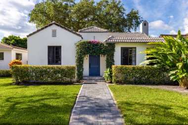 Modern mimari tasarım, ahşap mobilya, güzel yeşil bitki örtüsü, Mavi gökyüzü bulutları ve doğa sergilenmektedir..