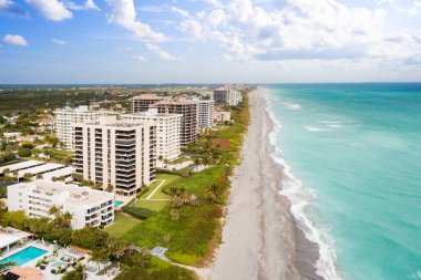 Florida, ABD 'deki hava aracı fotoshoot, ticari alan, lüks evler, binalar ve malikaneler, turkuaz suyu, mavi gökyüzü ve su kanalı etrafında bol miktarda tropikal bitki örtüsü.