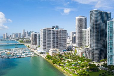 Florida, ABD 'deki hava aracı fotoshoot, ticari alan, lüks evler, binalar ve malikaneler, turkuaz suyu, mavi gökyüzü ve su kanalı etrafında bol miktarda tropikal bitki örtüsü.