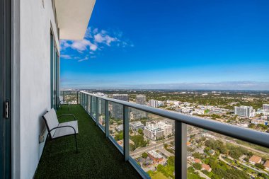 Florida, ABD 'de bir balkon, ticari alan, lüks evler, binalar ve malikaneler, turkuaz suyu, mavi gökyüzü ve su kanalı etrafında bol miktarda tropikal bitki örtüsü.