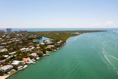 Florida, ABD 'deki hava aracı fotoshoot, ticari alan, lüks evler, binalar ve malikaneler, turkuaz suyu, mavi gökyüzü ve su kanalı etrafında bol miktarda tropikal bitki örtüsü.