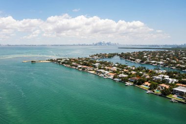 Florida, ABD 'deki hava aracı fotoshoot, ticari alan, lüks evler, binalar ve malikaneler, turkuaz suyu, mavi gökyüzü ve su kanalı etrafında bol miktarda tropikal bitki örtüsü.