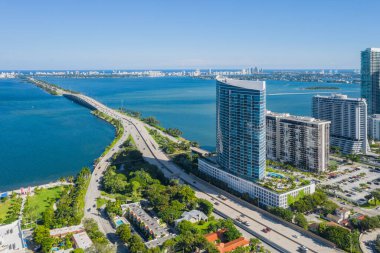 Florida, ABD 'deki hava aracı fotoshoot, ticari alan, lüks evler, binalar ve malikaneler, turkuaz suyu, mavi gökyüzü ve su kanalı etrafında bol miktarda tropikal bitki örtüsü.