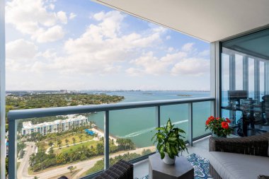 Florida, ABD 'de bir balkon, ticari alan, lüks evler, binalar ve malikaneler, turkuaz suyu, mavi gökyüzü ve su kanalı etrafında bol miktarda tropikal bitki örtüsü.