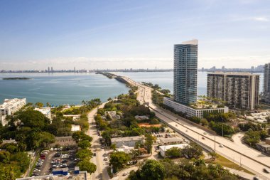 Florida, ABD 'deki hava aracı fotoshoot, ticari alan, lüks evler, binalar ve malikaneler, turkuaz suyu, mavi gökyüzü ve su kanalı etrafında bol miktarda tropikal bitki örtüsü.