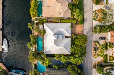 Florida, ABD 'deki hava aracı fotoshoot, ticari alan, lüks evler, binalar ve malikaneler, turkuaz suyu, mavi gökyüzü ve su kanalı etrafında bol miktarda tropikal bitki örtüsü.