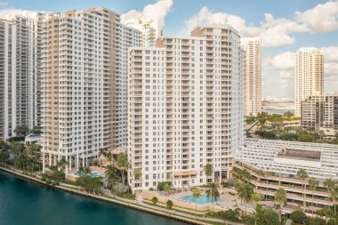 Florida, ABD 'deki hava aracı fotoshoot, ticari alan, lüks evler, binalar ve malikaneler, turkuaz suyu, mavi gökyüzü ve su kanalı etrafında bol miktarda tropikal bitki örtüsü.