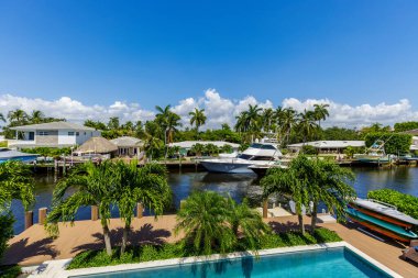 Florida, ABD 'deki hava aracı fotoshoot, ticari alan, lüks evler, binalar ve malikaneler, turkuaz suyu, mavi gökyüzü ve su kanalı etrafında bol miktarda tropikal bitki örtüsü.