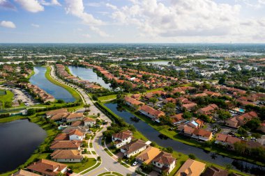 Florida, ABD 'deki hava aracı fotoshoot, ticari alan, lüks evler, binalar ve malikaneler, turkuaz suyu, mavi gökyüzü ve su kanalı etrafında bol miktarda tropikal bitki örtüsü.