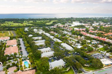 Florida, ABD 'deki hava aracı fotoshoot, ticari alan, lüks evler, binalar ve malikaneler, turkuaz suyu, mavi gökyüzü ve su kanalı etrafında bol miktarda tropikal bitki örtüsü.