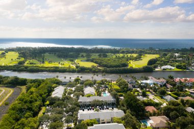 Florida, ABD 'deki hava aracı fotoshoot, ticari alan, lüks evler, binalar ve malikaneler, turkuaz suyu, mavi gökyüzü ve su kanalı etrafında bol miktarda tropikal bitki örtüsü.