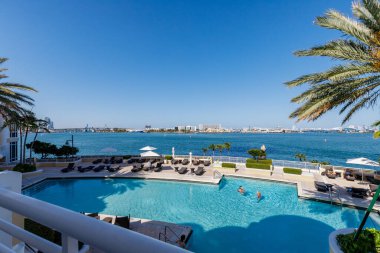 Florida, ABD. Eylül: Yüzme havuzu, yapay çimen, taş zemin, ağaçlar, sandalyeler ve şemsiyeli modern bir evin arka bahçesi.