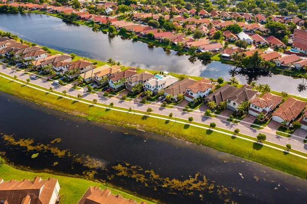 Aerial drone photoshoot Footage in Florida, USA, commercial area, luxury houses, buildings and mansions, abundant tropical vegetation around the beach with turquoise water, blue sky and water canal.