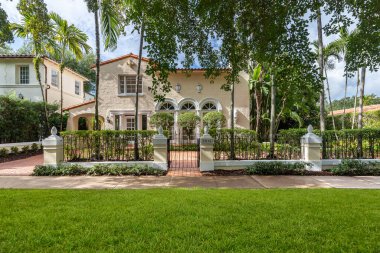 Florida, ABD. Ocak: Yüzme havuzu, yapay çimenler, taş patika, ağaçlar, sandalyeler ve şemsiyesi olan modern bir evin arka bahçesi.