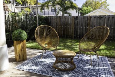 Florida, ABD. Ocak: Yüzme havuzu, yapay çimenler, taş patika, ağaçlar, sandalyeler ve şemsiyesi olan modern bir evin arka bahçesi.