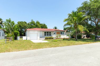 Yeşil çimlerin önünde iki penceresi olan tek bir aile evi.