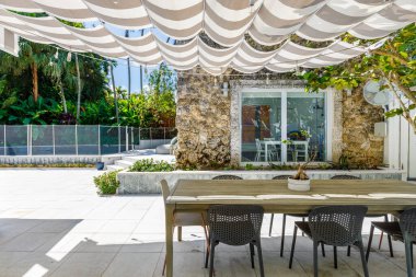 Masası olan bir teras ve gölgelik altında sandalyeler.