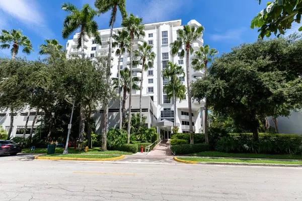 a large apartment building with palm trees in front
