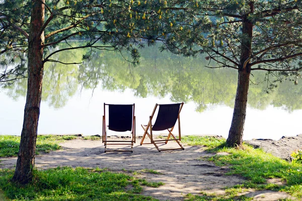 Two empty chairs near river. Couple chairs for rest in vacations.