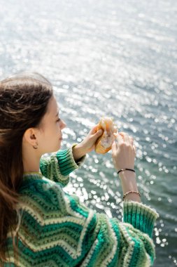 Türkiye 'de bulanık deniz kenarında elinde ekmek tutan bulanık esmer kadının yan görüntüsü 