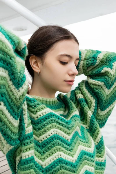 stock image Pretty young woman in knitted sweater touching hair on yacht 