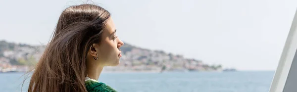 Side view of young brunette woman looking at blurred sea and Princess islands in Turkey, banner — Stock Photo