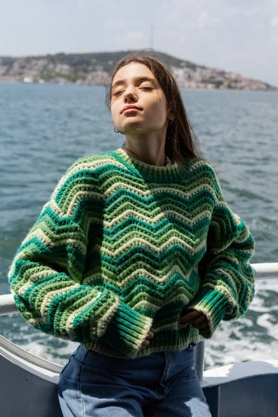 Young woman in knitted sweater standing on yacht with sea and Princess islands at background in Turkey — Stock Photo