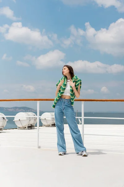 Young woman in sweater and jeans standing on ferry boat with sea at background in Turkey — Stock Photo