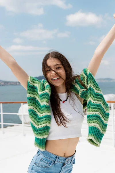 Cheerful young woman in top and sweater looking at camera during cruise on ferry boat in Turkey — Stock Photo