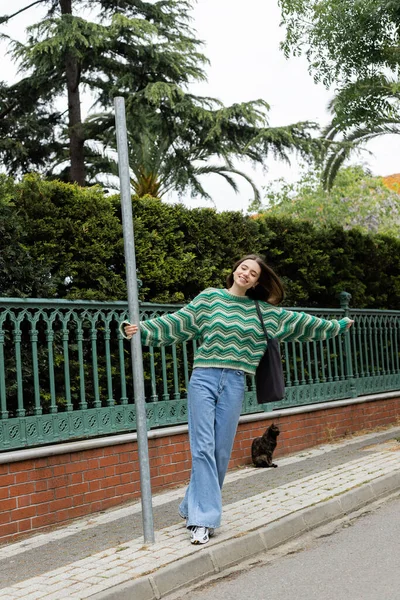 Femme positive en pull et jeans marchant dans la rue à Istanbul — Photo de stock