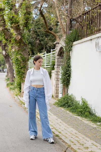 Стильная брюнетка в рубашке и джинсах стоит на городской улице в Стамбуле — стоковое фото
