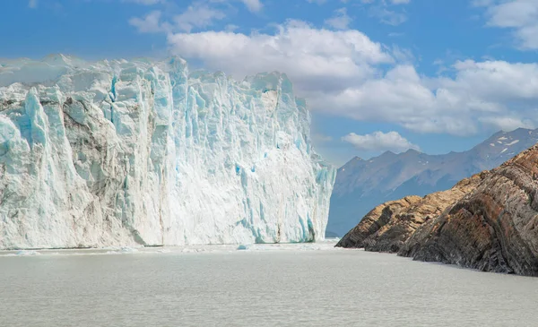 Glacier ice wall in Patagonia, ice texture, mountains and blue sky.